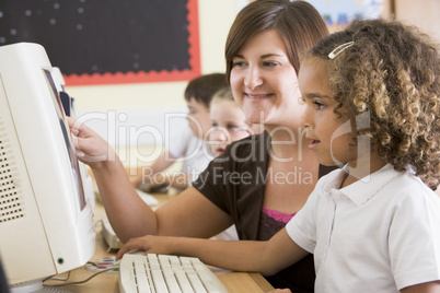 A girl and her teacher working on a computer at primary school