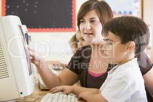 A boy and his teacher working on a computer at primary school