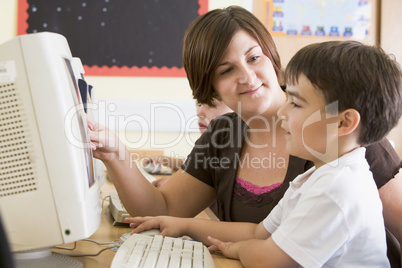 A boy and his teacher working on a computer at primary school