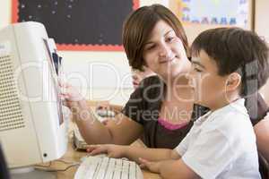 A boy and his teacher working on a computer at primary school