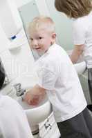 A boy washing his hands in a primary school bathroom