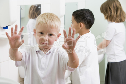 A boy displaying his hands in a primary school bathroom