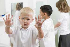 A boy displaying his hands in a primary school bathroom