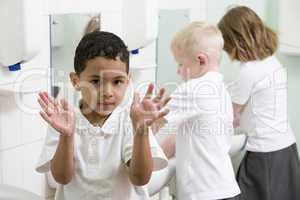 A boy displaying his hands in a primary school bathroom