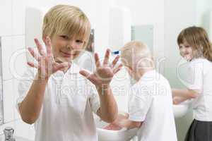 A boy displaying his hands in a primary school bathroom