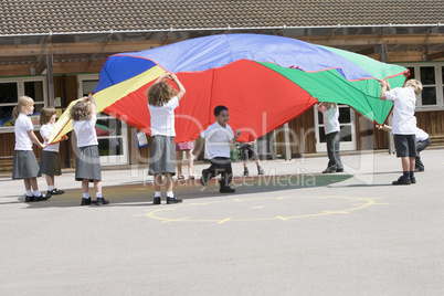 Young children playing with a parachute in a playground