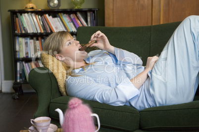 Frau liegt im Schlafanzug auf dem Sofa