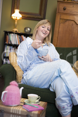 Eine junge Frau sitzt im Pyjama auf dem Sofa