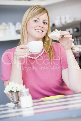 Eine blonde Frau hält Tasse und Gebäck in der Hand