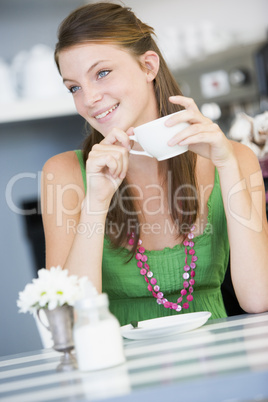 Junge dunkelhaarige Frau hält eine weisse Tasse