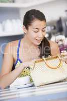 Eine junge Frau sitzt im Cafè und durchsucht ihre Handtasche