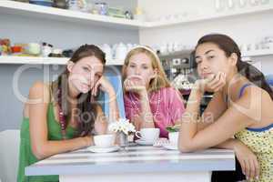 Drei junge Frauen sitzen gelangweilt  in einem Cafè