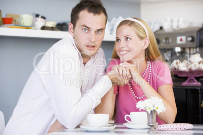 Ein junges Pärchen sitzt verliebt im Cafè