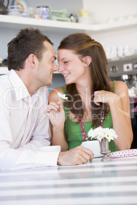 Ein junges Pärchen sitzt verliebt im Cafè