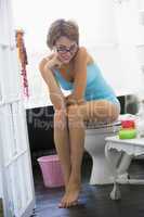 Eine junge Frau mit Brille sitzt im Bad