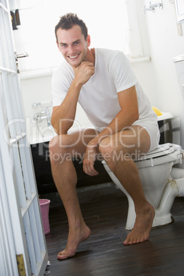 Ein junger Mann in Unterwäsche sitzt auf der Toilette