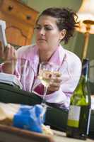 A young woman in her pyjamas drinking wine and frowning at her t
