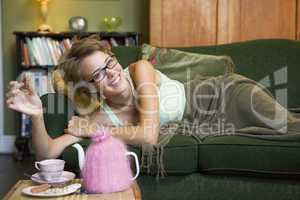 A young woman lying on her couch eating biscuits