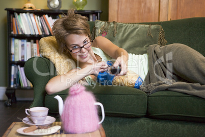 A young woman lying on her couch watching television