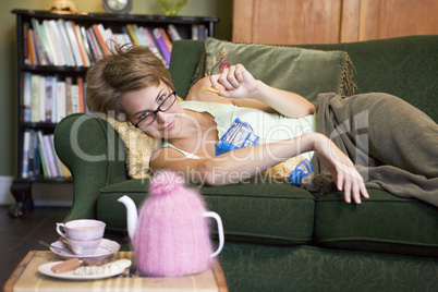 A young woman lying on her couch eating