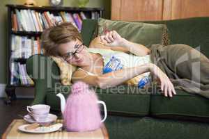 A young woman lying on her couch eating