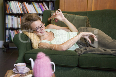 A young woman lying on her couch eating chocolate