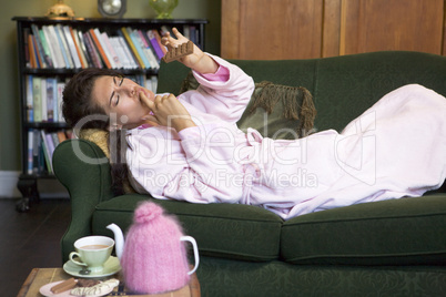 A young woman lying on her couch eating chocolate