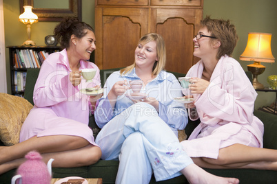 Three young women drinking tea together in their pyjamas