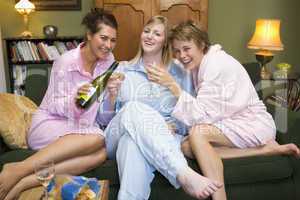 Three young women drinking wine together in their pyjamas