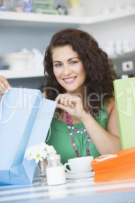 A young woman with shopping bags sitting in a cafe