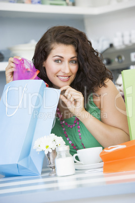 A young woman with shopping bags sitting in a cafe