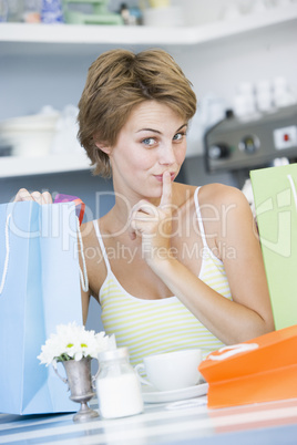 A young woman sitting in a cafe with shoping bags