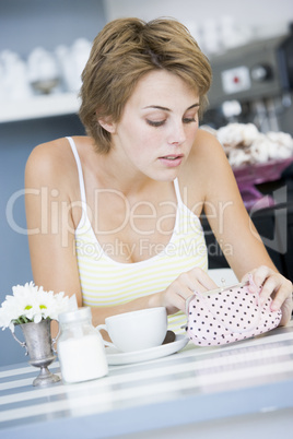 A young woman sitting in a cafe looking into her purse
