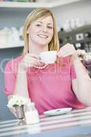 A young woman sitting in a cafe drinking tea