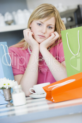 A young woman sitting in a cafe with shopping bags