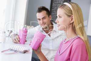 A young couple drinking milkshakes in a cafe