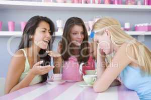 Two young women enjoying a tea party while one sits apart wearin