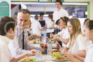 A teacher eating lunch with his students in the school cafeteria