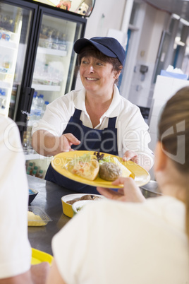 A woman serving lunch to high school students