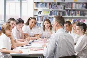 Schoolchildren and teacher studying in school library