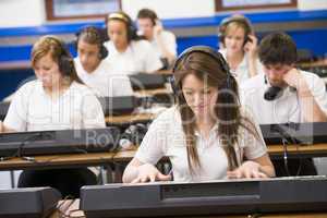 Schoolchildren practicing on a keyboard in music class