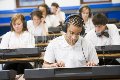 Schoolchildren practicing on a keyboard in music class