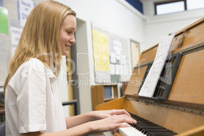 Schoolgirl playing piano in music class