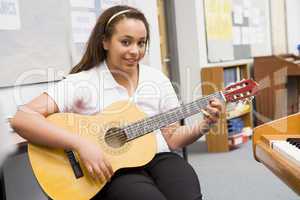 Schoolgirl playing guitar in music class