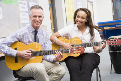 Schoolgirl and teacher playing guitar in music class