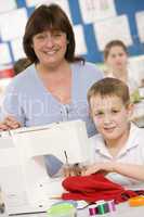 Teacher and schoolboy using a sewing machine in sewing class