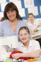 Teacher and schoolgirl using a sewing machine in sewing class