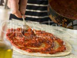 Spooning Tomato sauce onto a Pizza Base