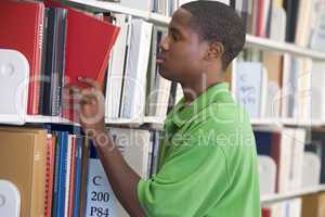 University student slecting book from library shelf