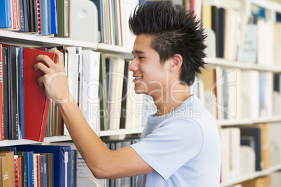 University student selecting book from library shelf